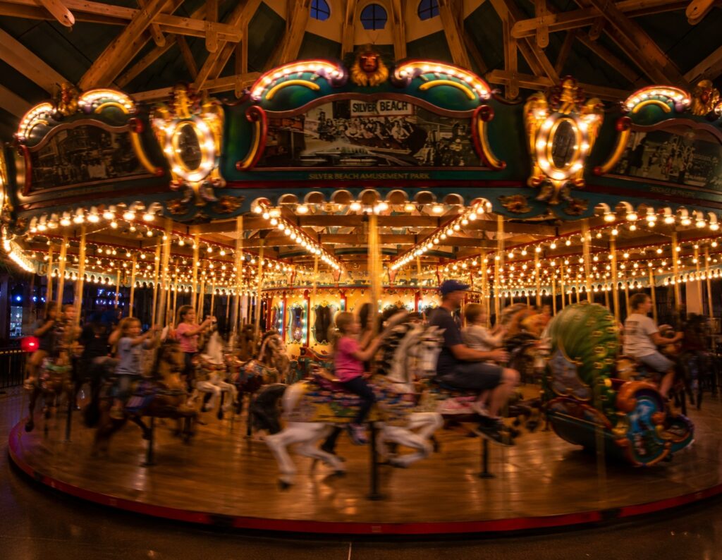 Families riding the Silver Beach Carousel in St. Joseph, Michigan during an evening ride with colorful lights and motion blur.