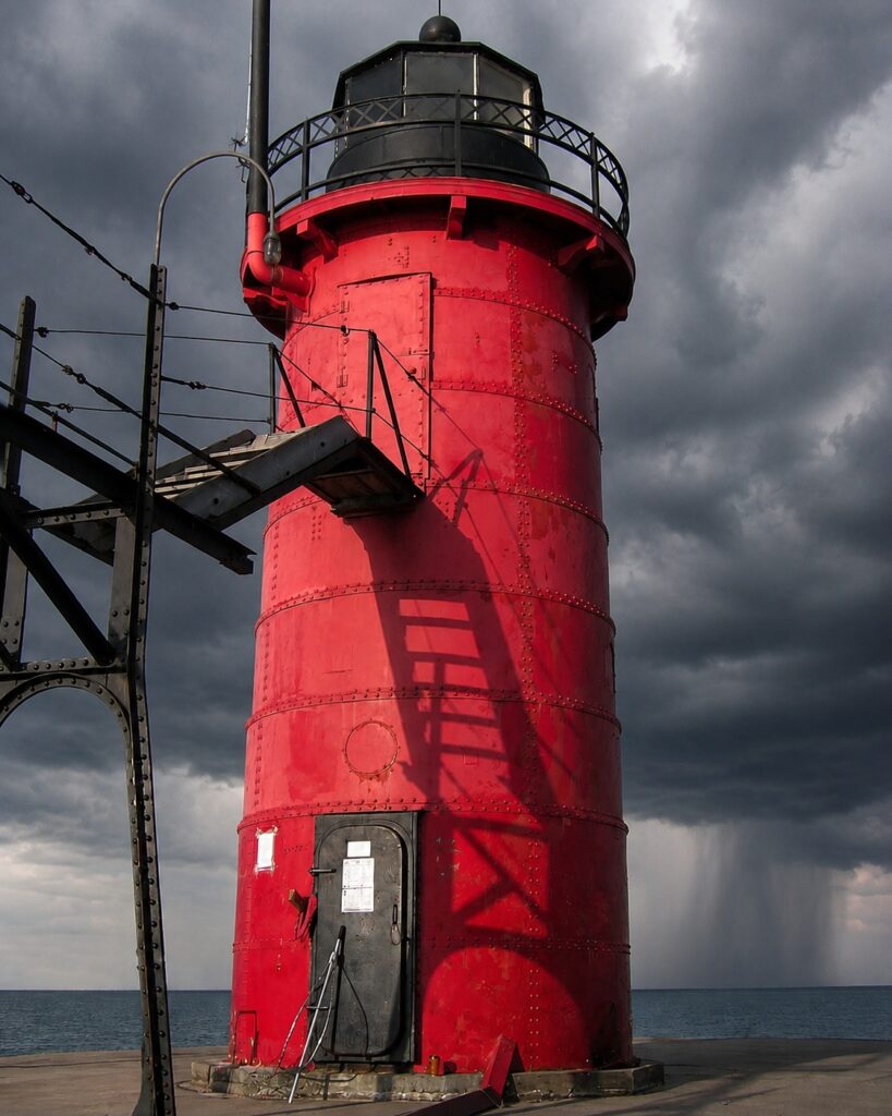 The red South Haven Lighthouse stands beneath dark storm clouds as a rain downburst falls over Lake Michigan near the South Pier.