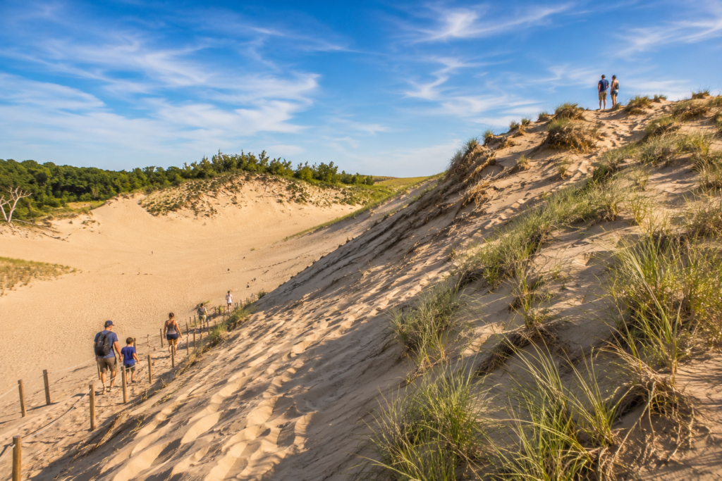 State Parks in Southwest Michigan at Warren Dunes State Park with hikers exploring towering sand dunes on a sunny summer morning.