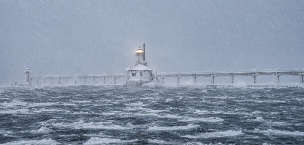 Snow-covered St. Joseph lighthouse surrounded by choppy water and floating ice during winter in Southwest Michigan